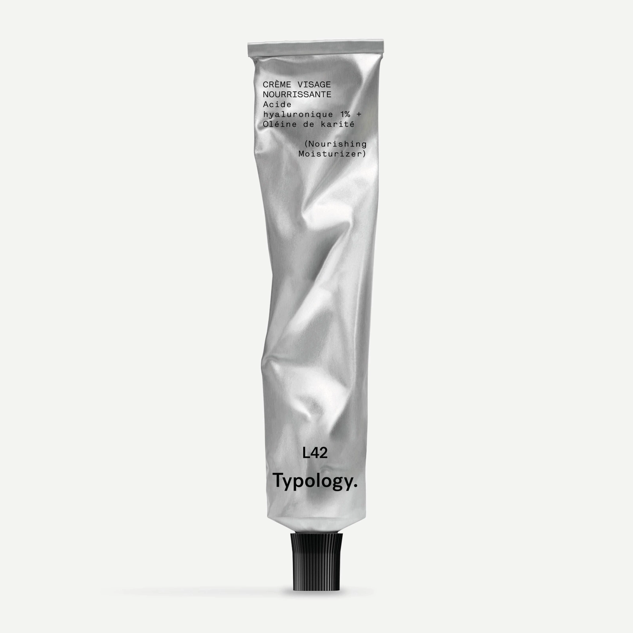 A product photograph of a skincare tube featuring a metallic silver laminate pouch with a black cap, shot against a neutral white background.