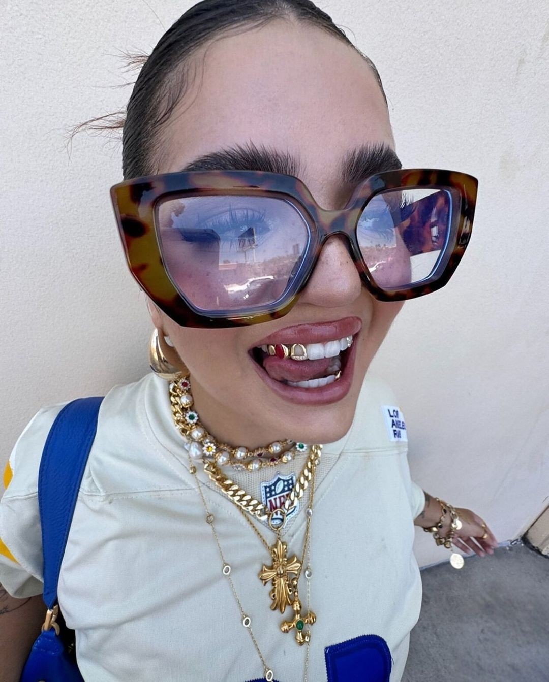 Model wearing a green agate cross pendant necklace and sage/gold resin ring from Grisé NYC.