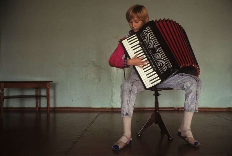 A boy plays an accordion in Russia, 1992. Photo by Ljalja Kuznetsova.