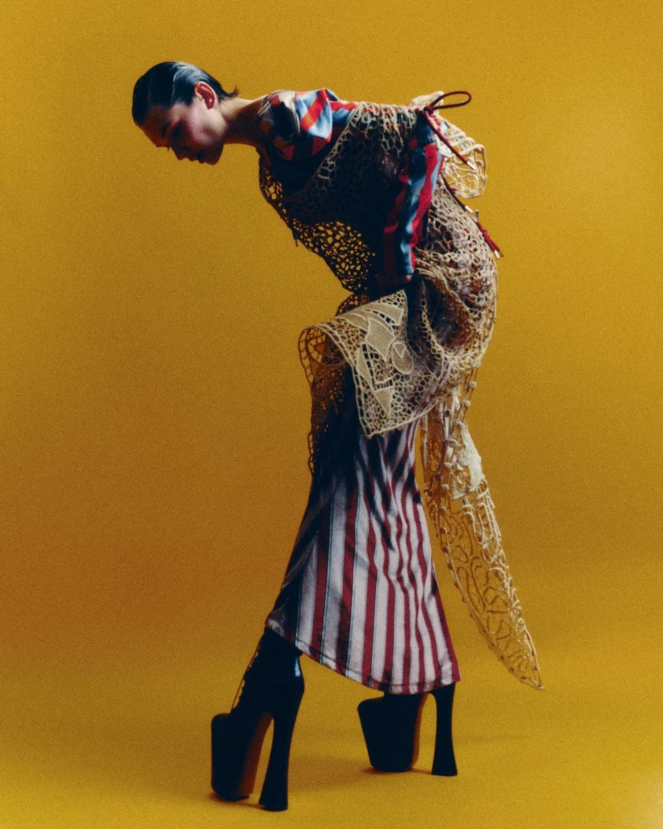 Fashion editorial portrait photograph shot against a vibrant golden-yellow background.